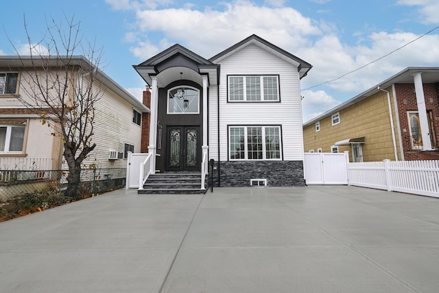 traditional-style home with french doors, stone siding, and fence