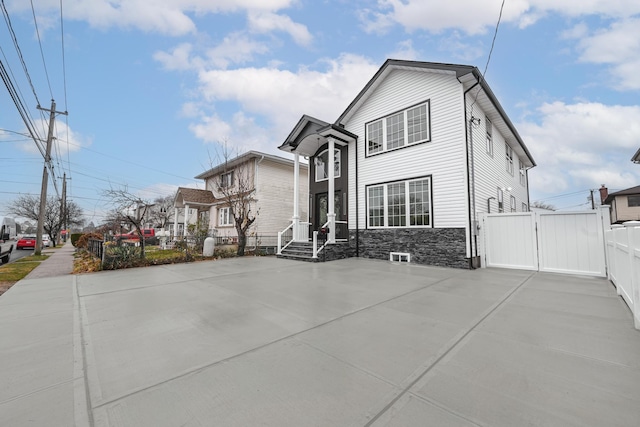 exterior space with a gate, fence, and stone siding