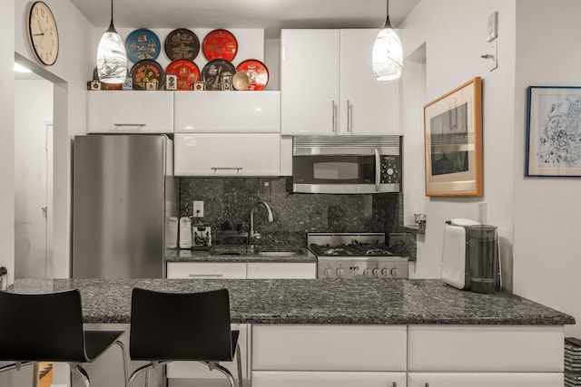 kitchen featuring a sink, tasteful backsplash, stainless steel appliances, white cabinets, and hanging light fixtures