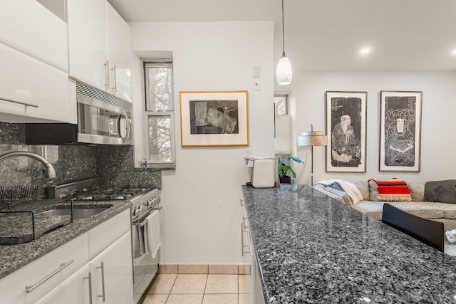 kitchen featuring light tile patterned floors, a sink, stainless steel appliances, white cabinets, and tasteful backsplash