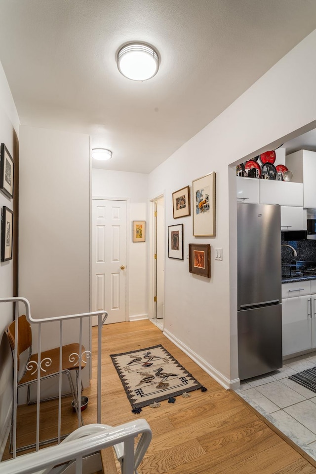 corridor with light wood-style flooring and baseboards