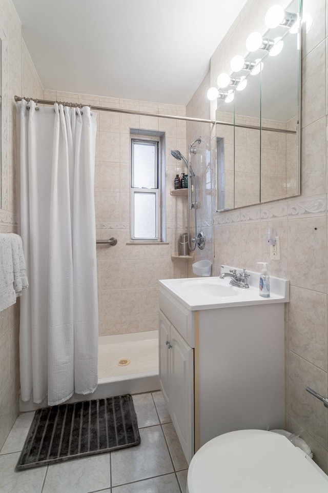 bathroom featuring tile patterned flooring, toilet, vanity, a stall shower, and tile walls