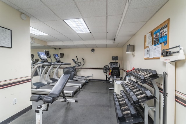 gym with a drop ceiling and baseboards