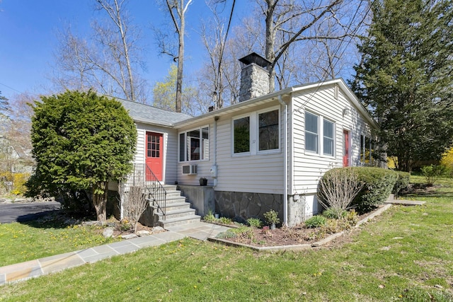 view of front of home with entry steps, a chimney, and a front yard