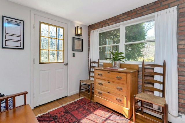 doorway to outside featuring brick wall and wood finished floors