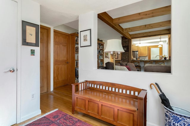 interior space featuring beamed ceiling, wood finished floors, refrigerator, and a sink