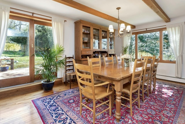 dining area with beam ceiling, hardwood / wood-style flooring, an inviting chandelier, and a healthy amount of sunlight