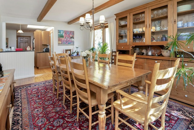 dining space featuring beam ceiling, a notable chandelier, and light wood-style floors