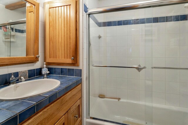 bathroom featuring vanity and bath / shower combo with glass door