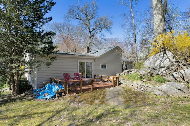 rear view of house featuring a lawn, a chimney, and a wooden deck