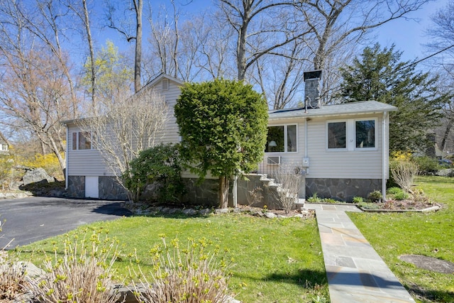 view of front facade featuring a chimney and a front yard