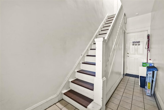 staircase featuring baseboards and tile patterned flooring