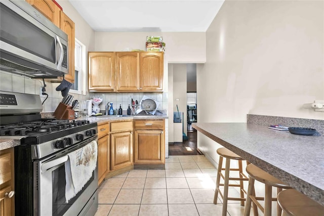 kitchen with light tile patterned floors, stainless steel appliances, and tasteful backsplash