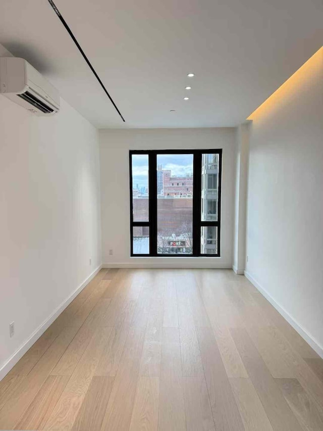 108-15 72nd Ave Unit 5A, Forest Hills, NY 11375 - empty room with an AC wall unit, light wood finished floors, baseboards, and recessed lighting