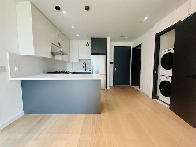 108-15 72nd Ave Unit 5A, Forest Hills, NY 11375 - kitchen with estacked washer and dryer, fridge, light countertops, light wood-type flooring, and a peninsula