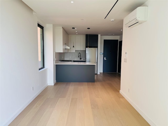 108-15 72nd Ave Unit 5A, Forest Hills, NY 11375 - kitchen with a wall unit AC, freestanding refrigerator, light wood-type flooring, light countertops, and a peninsula