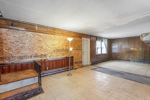 interior space with a baseboard heating unit, tile patterned floors, and wood walls