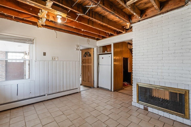 spare room with beam ceiling, light tile patterned floors, a brick fireplace, baseboard heating, and wood ceiling