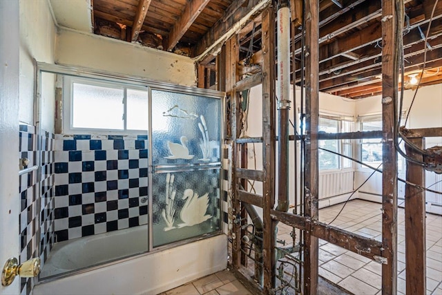 bathroom with combined bath / shower with glass door, plenty of natural light, and tile patterned flooring