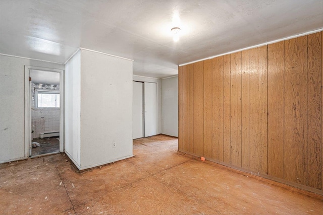 unfurnished room featuring baseboard heating and wood walls