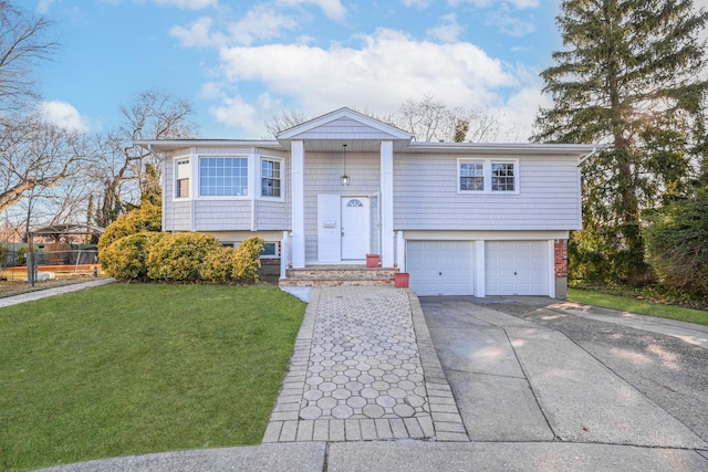 raised ranch with a garage, driveway, and a front lawn