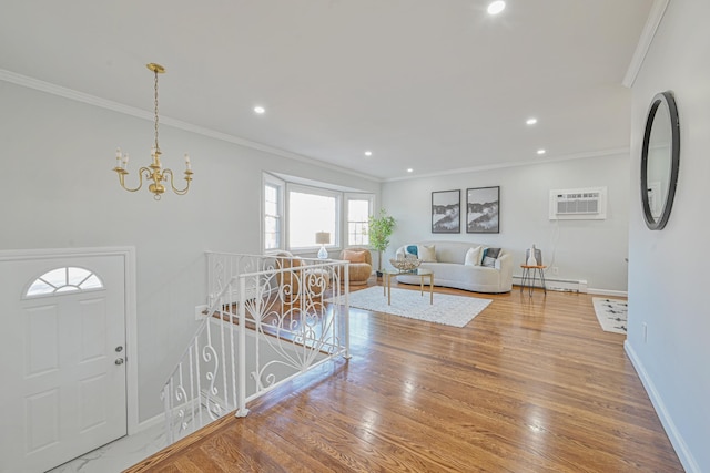 living room featuring ornamental molding, wood finished floors, a notable chandelier, a wall mounted AC, and a baseboard radiator