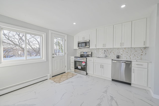 kitchen featuring a sink, stainless steel appliances, baseboard heating, white cabinetry, and backsplash