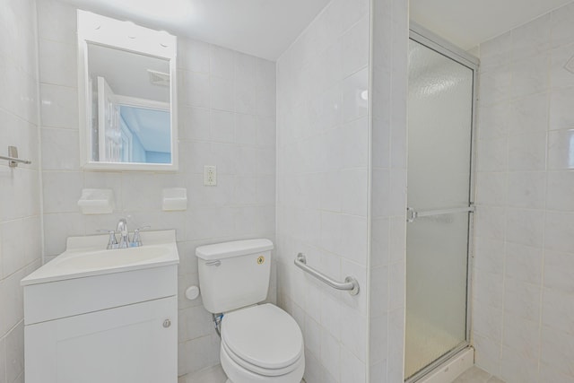 bathroom with a shower stall, tile walls, vanity, and toilet