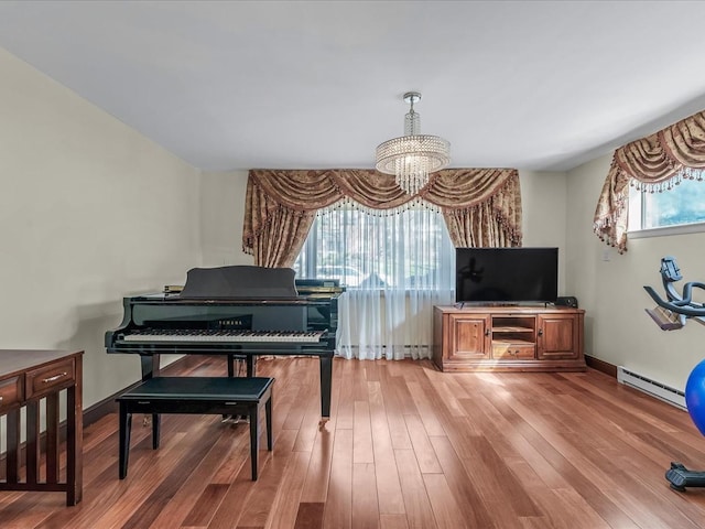 living area featuring light wood-type flooring, a baseboard radiator, baseboards, and a notable chandelier