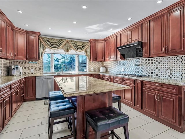 kitchen with a breakfast bar area, light stone counters, stainless steel appliances, exhaust hood, and reddish brown cabinets