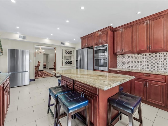 kitchen featuring a kitchen breakfast bar, visible vents, reddish brown cabinets, and stainless steel appliances