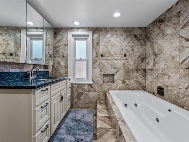 bathroom featuring vanity, a whirlpool tub, recessed lighting, marble finish floor, and tile walls