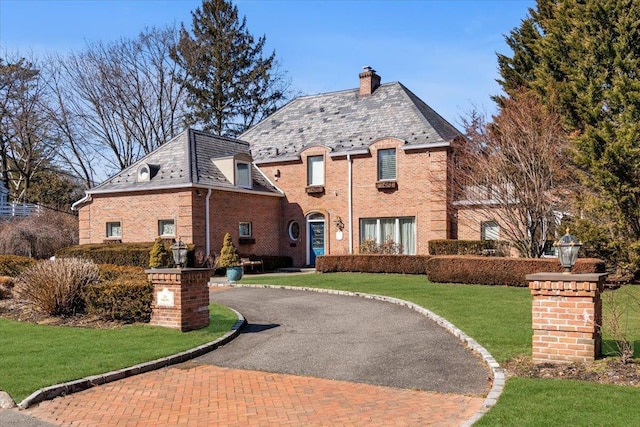 exterior space with a high end roof, brick siding, and a front yard