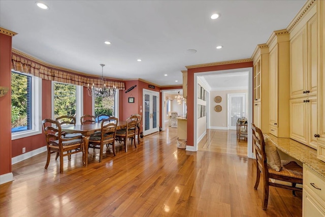dining room featuring light wood-style floors, baseboards, an inviting chandelier, and crown molding