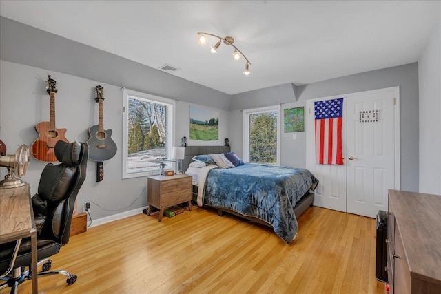 bedroom with visible vents, baseboards, multiple windows, and light wood-style floors