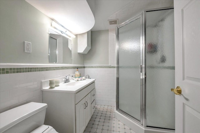 bathroom featuring vanity, a stall shower, a wainscoted wall, visible vents, and tile walls