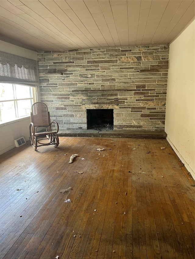 unfurnished living room featuring a stone fireplace, wooden ceiling, visible vents, and wood-type flooring