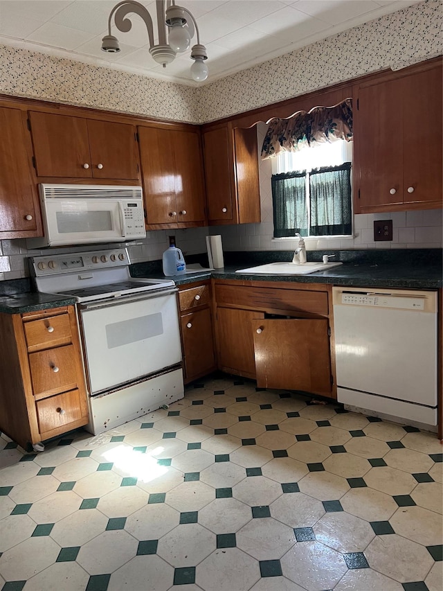 kitchen featuring a sink, dark countertops, white appliances, decorative backsplash, and light floors