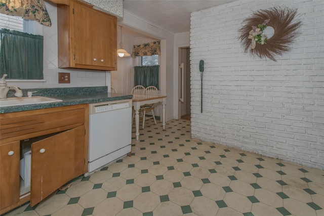 kitchen featuring brick wall, ornamental molding, a sink, dishwasher, and dark countertops