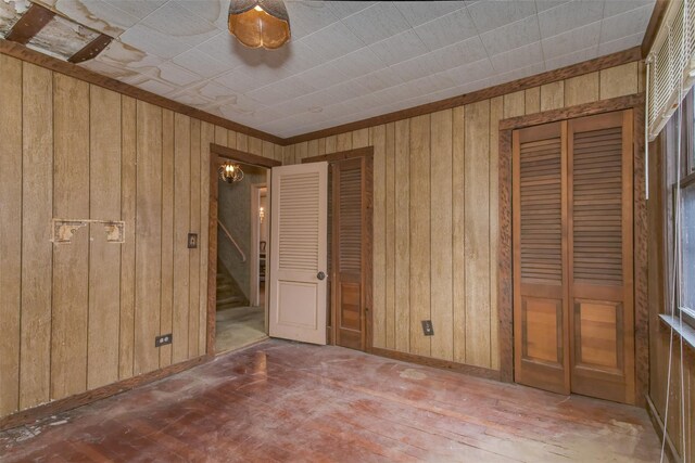 unfurnished bedroom with wooden walls, baseboards, and multiple closets