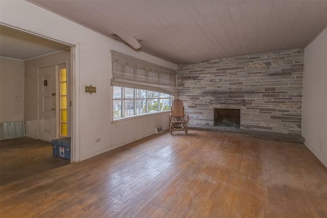 unfurnished living room with visible vents, a stone fireplace, hardwood / wood-style floors, and ornamental molding