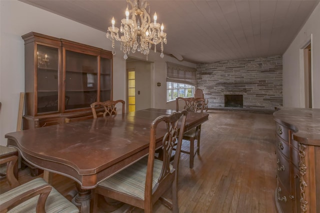 dining space featuring a stone fireplace, wooden ceiling, an inviting chandelier, and wood-type flooring