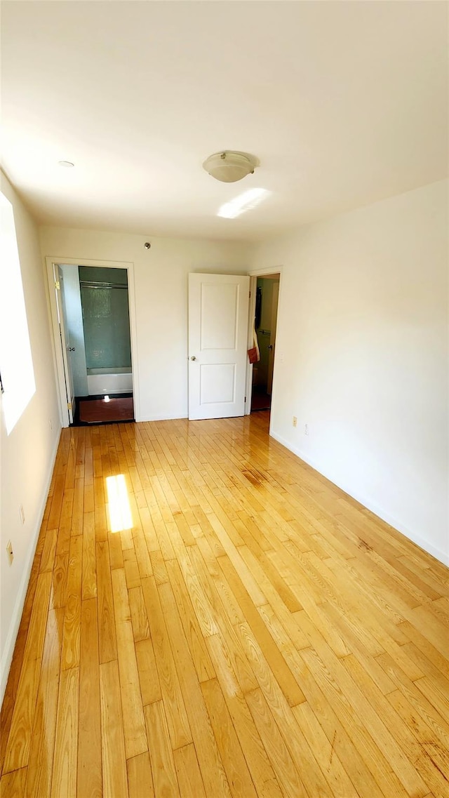 spare room with light wood-type flooring and baseboards