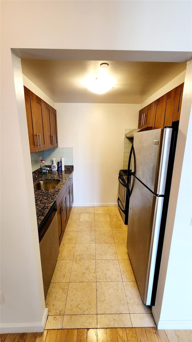 kitchen with baseboards, light tile patterned floors, decorative backsplash, stainless steel appliances, and a sink