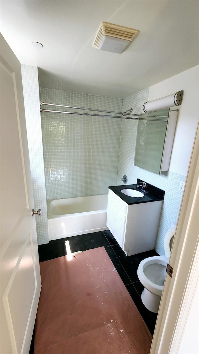 bathroom featuring toilet, shower / bathtub combination, tile walls, tile patterned flooring, and vanity