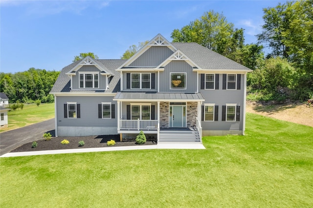 view of front of house featuring stone siding, driveway, covered porch, and a front lawn