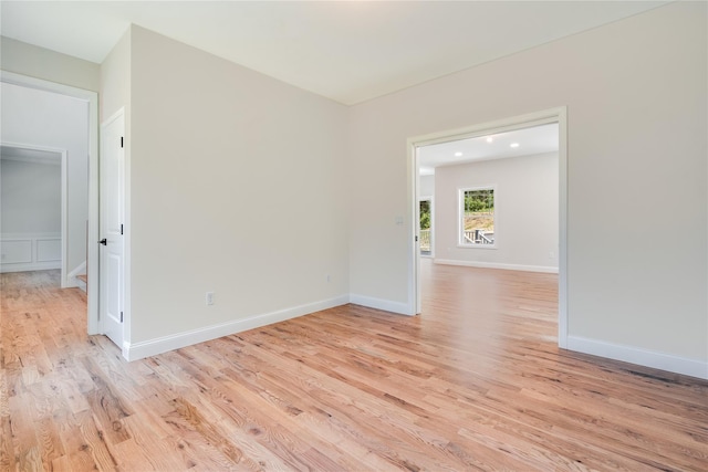 spare room featuring baseboards and light wood finished floors