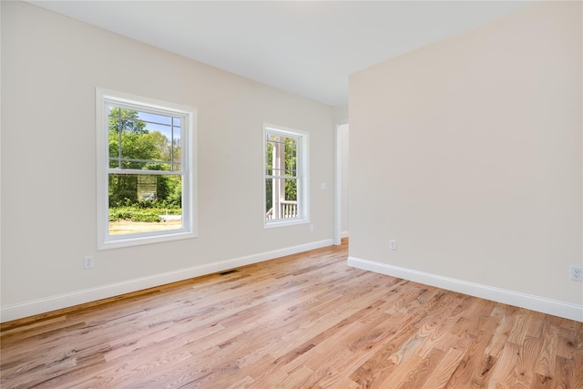 empty room with visible vents, light wood-type flooring, and baseboards