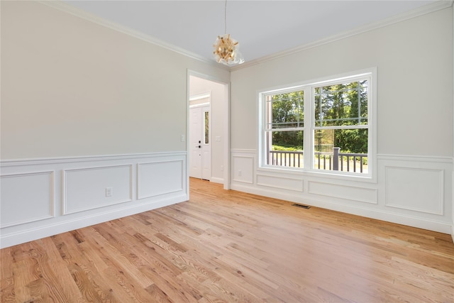 spare room featuring crown molding, light wood-style floors, visible vents, and a chandelier