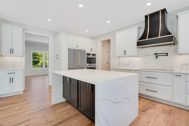 kitchen with a center island, decorative backsplash, stainless steel appliances, custom exhaust hood, and white cabinetry